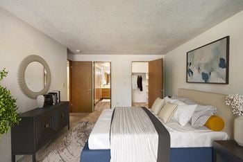 A bedroom with a bed and a dresser and a mirror